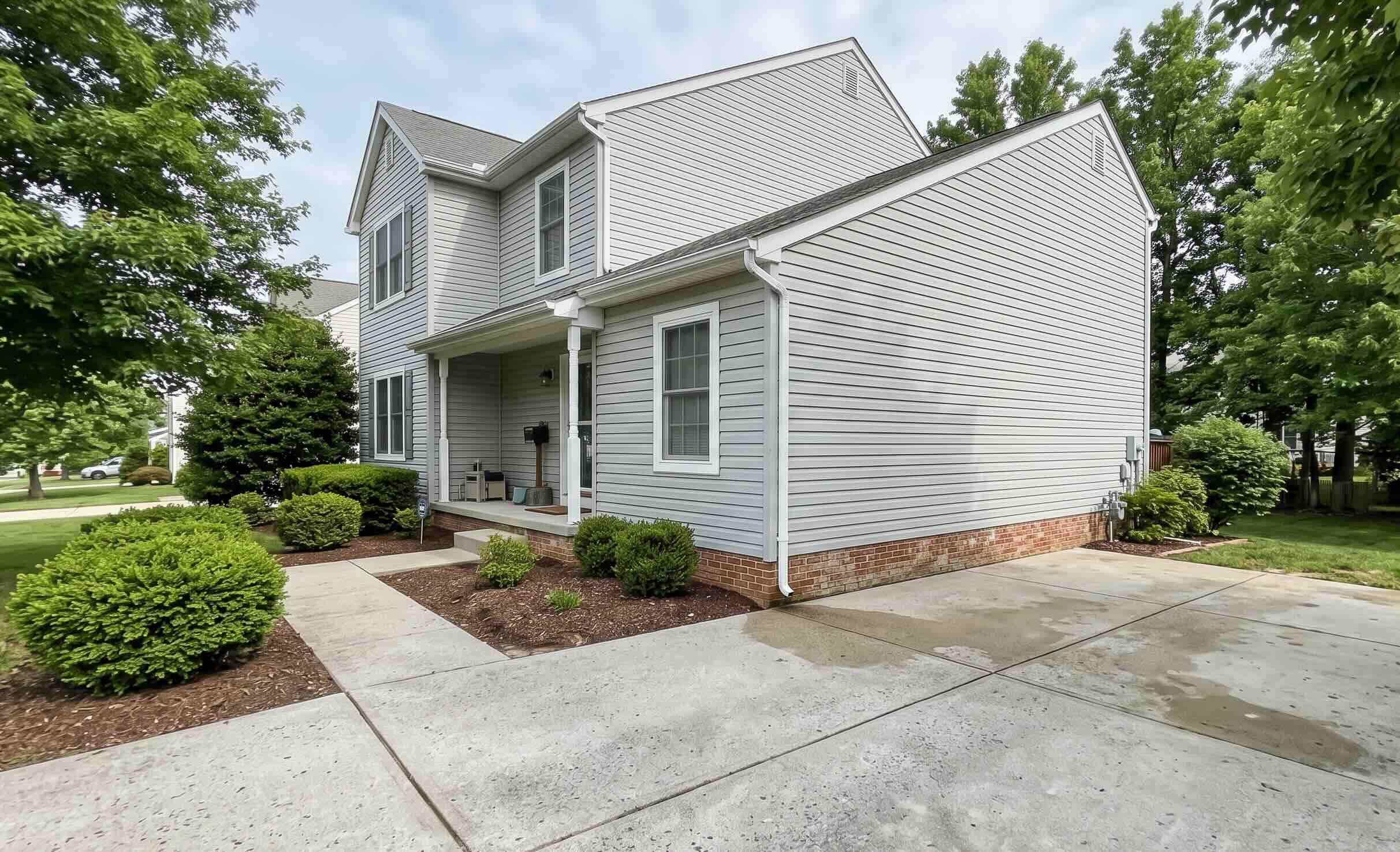 Photo of Clean vinyl siding, concrete driveway, and front walkway outside a suburban Maryland home, demonstrating the benefits of professional exterior power washing in Harford County MD.